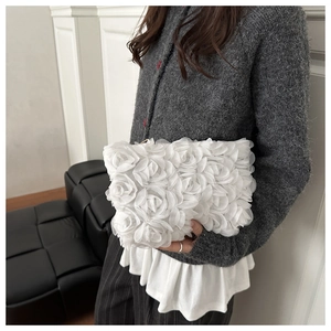 Close-up of white floral mesh handbag with 3D organza roses held by a fashion model