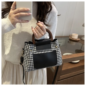 Detail of houndstooth tote with wooden handle and leather pocket shown in lifestyle setting