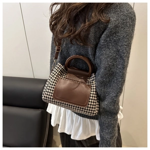 Detail of color-block houndstooth boston bag with brown leather strap worn by a model