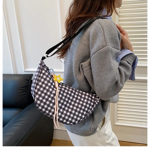 Detail of checkered crescent shoulder bag with yellow star charm and pink tassel accent