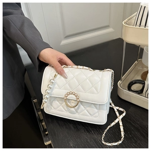 Detailed macro view of white quilted crossbody bag featuring a pearl ring metal lock