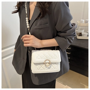 Close-up of quilted white crossbody bag with pearl chain strap and circular metal buckle