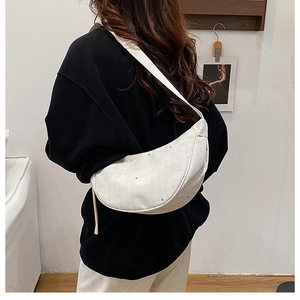 Detail of checkered dumpling crossbody bag with star pattern and wide strap on shoulder
