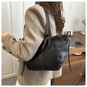Detail of black pebbled leather tote bag with white contrast stitching on model