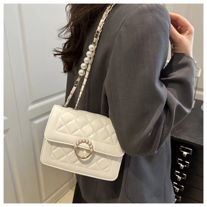 Detailed close-up of a white quilted crossbody bag with pearl chain and golden clasp