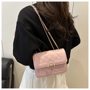 Detail view of a pink quilted crossbody bag with pearl buckle and metal chain strap
