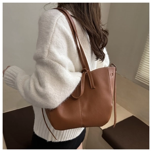 Close-up of brown litchi grain leather tote bag with drawstring detail on model