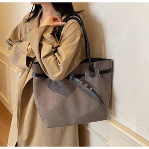 Détail du sac cabas en daim gris avec ceintures noires et œillets métalliques décoratifs