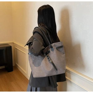 Detailansicht grauer Shopper aus Canvas mit Lederriemen und silbernen Metallösen am Rand