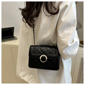 Detail of black quilted crossbody bag with pearl buckle and leather chain strap