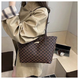 Detail of coffee brown tote bag with M-letter pattern and golden metal buckle