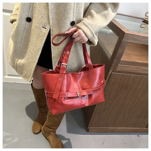 Close-up of red leather tote bag featuring premium buckle strap and vintage texture