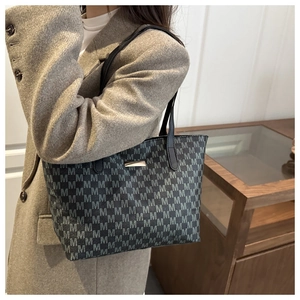Close-up of charcoal grey tote bag with M-pattern print and gold metal nameplate