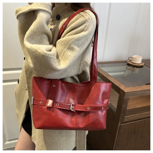 Detail of red oversized tote bag with silver buckle and natural leather texture