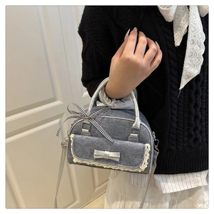 Macro shot of grey denim crossbody bag featuring delicate white lace trim and a cute bow