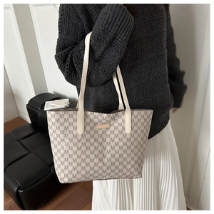 Detail of light beige tote bag with brown M-letter jacquard and leather handles
