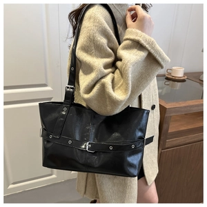Detailed shot of black oil wax leather tote bag featuring metallic eyelet strap detail
