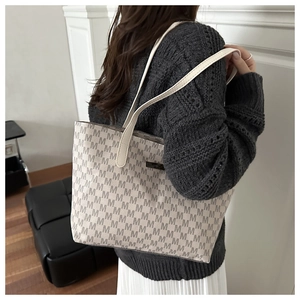 Close-up of beige tote bag with M-pattern print and long leather straps on model