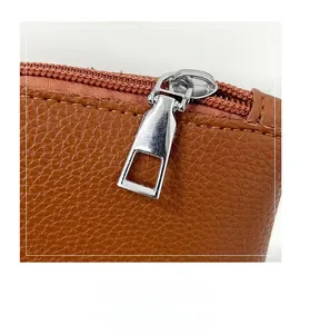 Detailed macro view of high-quality silver metal zipper on brown pebble leather tote bag