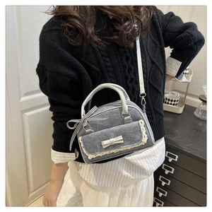 Detail of denim mini bowling bag with silver bow accent and lace trim on a model