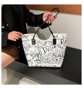 Dettaglio della borsa tote bianca con stampe graffiti nere e ciondolo a nuvola