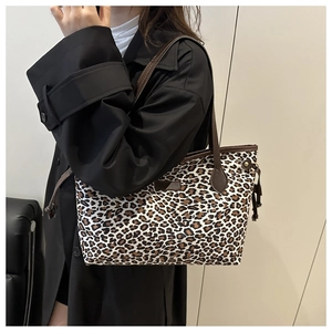 Détail du sac cabas en toile à imprimé léopard avec anses en cuir marron sur modèle