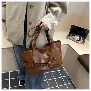 Detail of vintage brown leather tote bag featuring stylish cross straps and silver buckles
