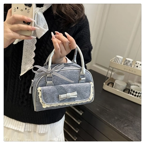 Detail of grey mini bowling bag featuring white lace trim and elegant ribbon bow accents