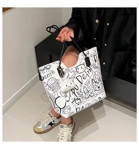 Dettaglio della borsa shopper bianca con graffiti neri e ciondolo a nuvola soffice