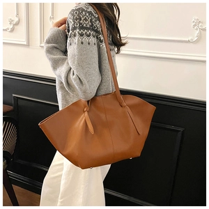 Detailed side view of caramel brown tote bag featuring wavy edges and side knot accents