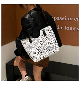 Dettaglio della borsa tote bianca con graffiti neri e sottili spalline resistenti