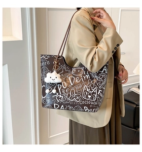 Dettaglio di una borsa shopper marrone con graffiti e un ciondolo a nuvola bianca morbida