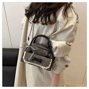 Detailed view of dark denim boston bag with lace trim and bow accent on trench coat