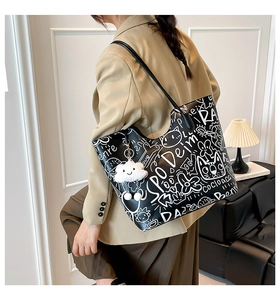Detail of graffiti pattern tote bag with white cloud plush charm in a chic interior setting