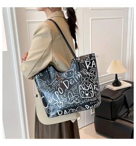 Detailed close-up of street style graffiti print on black faux leather tote bag