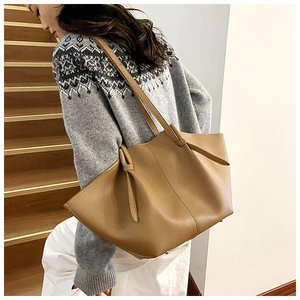 Detailed macro view of khaki lychee grain leather tote bag with stylish knot handle detail