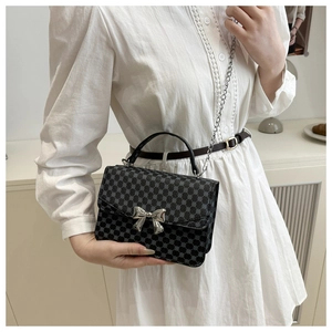 Detail of a chic small square bag with metallic butterfly buckle and silver chain strap