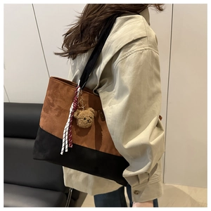 Détail du sac seau bicolore avec pendentif ours en peluche et cordon tissé décoratif