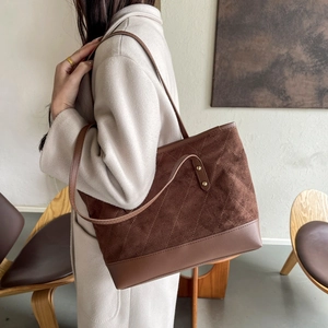 Détail du sac cabas en daim marron avec matelassage en losanges et base lisse