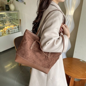 Close-up of vintage brown tote bag with suede quilting and gold rivet details