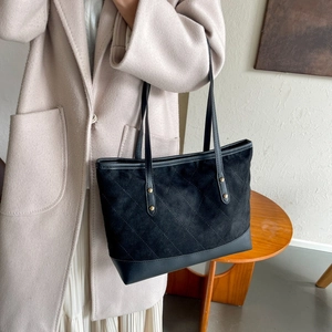 Détail du sac cabas noir avec coutures matelassées et rivets dorés sur de fines anses