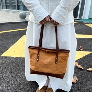 Close-up of brown quilted suede tote bag with slim handles and metallic rivet details