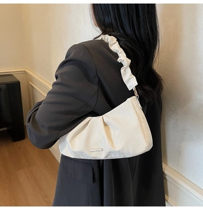 Detail view of white ruched shoulder bag with silver plaque and ruffled strap detail