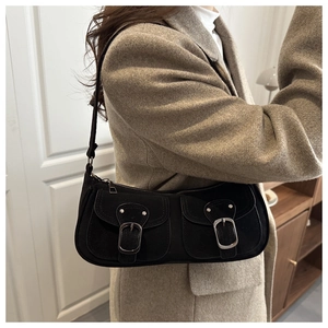 Detail of black retro baguette bag with dual front pockets and silver buckle accents