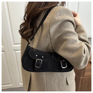 Detail of black suede underarm bag with silver square metal buckles in retro utility style