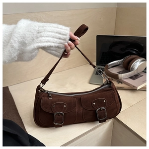 Macro shot of brown suede shoulder bag featuring retro double pockets and metal buckles