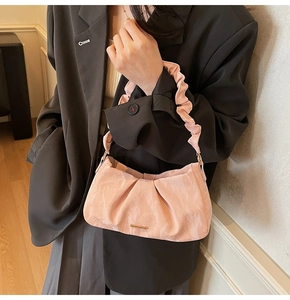 Dettaglio della borsa a mano in velluto rosa plissettato con finiture dorate
