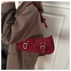 Detail of burgundy suede shoulder bag featuring silver metal buckles and chain strap detail