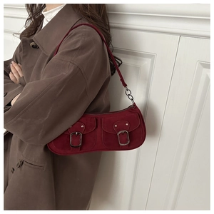 Sac sous le bras en daim rouge rétro avec boucles argentées porté par un mannequin