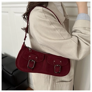 Detail of vintage burgundy shoulder bag featuring dual front pockets and buckle accents